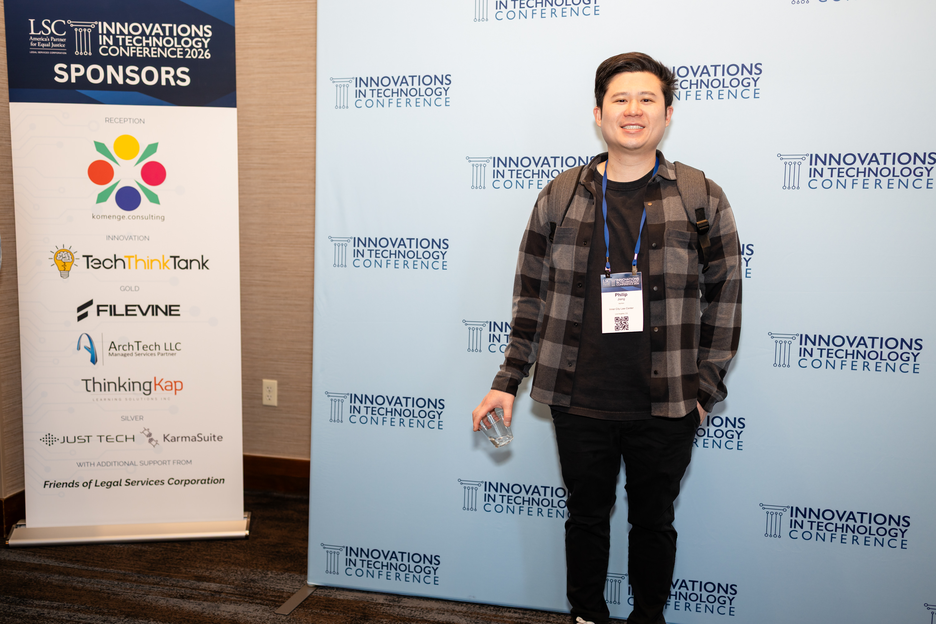 Attendee wearing a conference badge beside sponsor signage and an ITC photo backdrop