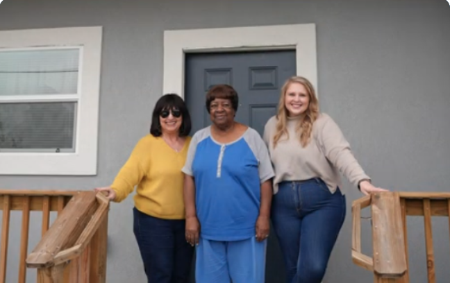 Julie with two people on the porch of her home